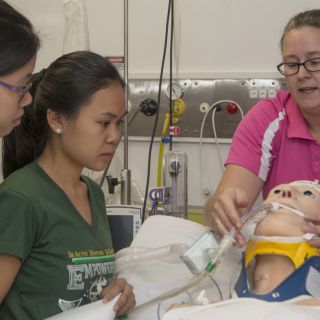 UC nursing student Lori Delaney showing the manikin to UST students