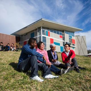 A group of students sit talking on a grassy hillside at the University's Bruce campus