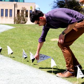 A staff member places a flag in the ground to support White Ribbon Day