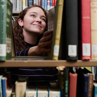 woman selecting book in library