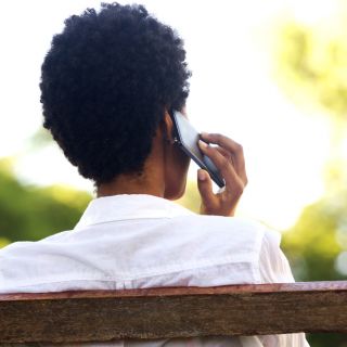 Image of a woman sitting on a park bench on the phone