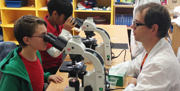 Image of a researcher teaching a student how to look through a microscope