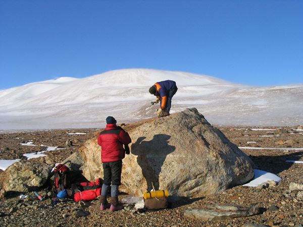 Dr Duanne White takes samples from a large boulder in Antarctica