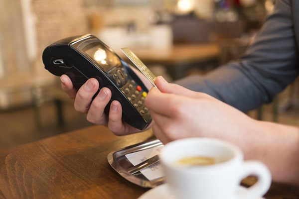 A person pays using contactless technology at a coffee shop