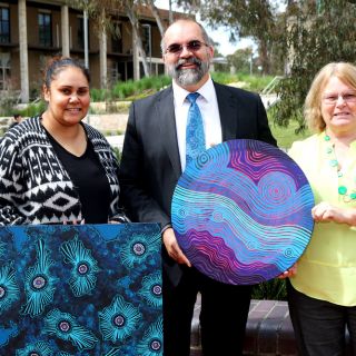 Tamara Murray, Professor Peter Radoll and Aunty Roslyn Brown with Krystal Hurst’s artworks ‘Waterholes and Ocean Waves’ and ‘Rock Pools’